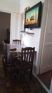 a dining room table with chairs and a television on a wall at Apto Central Barra de Imbé in Imbé