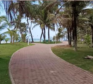 un sentiero in mattoni che conduce a una spiaggia con palme di Suspiro da Bahia Pé na areia a Salvador