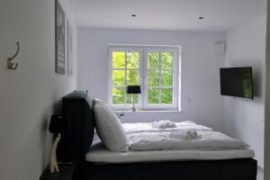 Bett in einem weißen Zimmer mit Fenster in der Unterkunft Muehlenblick 3 - Traumferien in Hage in Hage
