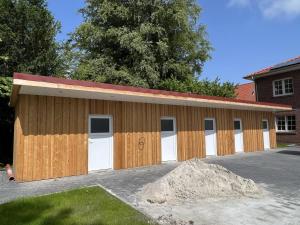 uma garagem de madeira com portas brancas e uma pilha de terra em Muehlenblick 3 - Traumferien in Hage em Hage