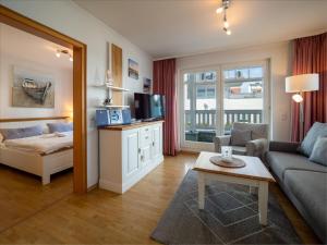 ein Wohnzimmer mit einem Sofa, einem Bett und einem TV in der Unterkunft Ferienwohnung 560 in der Villa Gudrun in Binz