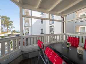 einen Balkon mit einem schwarzen Tisch und roten Stühlen in der Unterkunft Ferienwohnung 560 in der Villa Gudrun in Binz
