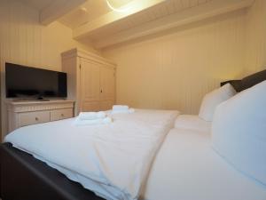 Schlafzimmer mit einem weißen Bett und einem Flachbild-TV in der Unterkunft Ferienhaus Marie in Binz