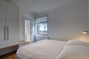 Habitación blanca con cama y ventana en Landhaus am Ufer - Wohnung 1, en Heiligenhafen
