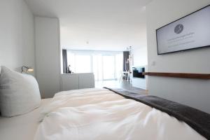 a white bedroom with a large bed and a television at Strandzeit Heiligenhafen in Heiligenhafen