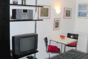 ein Wohnzimmer mit einem TV und einem Tisch mit Stühlen in der Unterkunft Apartmentvermittlung Mehr als Meer - Objekt 4 in Timmendorfer Strand