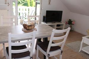a dining room with a wooden table and white chairs at Apartmentvermittlung Mehr als Meer - Objekt 24 in Niendorf