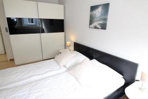 a bedroom with a white bed with a black headboard at Apartmentvermittlung Mehr als Meer - Objekt 8 in Niendorf