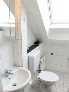 a white bathroom with a toilet and a sink at Apartmentvermittlung Mehr als Meer - Objekt 8 in Niendorf