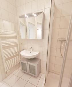 a white bathroom with a sink and a mirror at Apartmentvermittlung Mehr als Meer - Objekt 77 in Niendorf