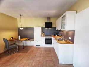 uma cozinha com armários brancos, uma mesa e um lavatório em Apartmentvermittlung Mehr als Meer - Objekt 23 em Niendorf