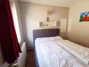 ein kleines Schlafzimmer mit einem weißen Bett darin in der Unterkunft Apartmentvermittlung Mehr als Meer - Objekt 23 in Niendorf