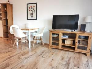 Apartmentvermittlung Mehr als Meer - Objekt 9 في نيندورف: غرفة معيشة فيها تلفزيون وطاولة وكراسي