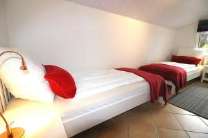 Habitación con 2 camas con almohadas rojas. en Apartmentvermittlung Mehr als Meer - Objekt 56, en Scharbeutz