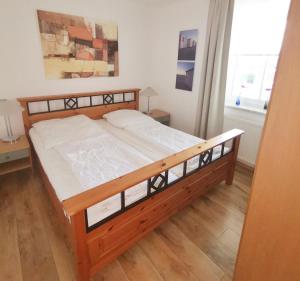 a wooden bed in a room with a window at Apartmentvermittlung Mehr als Meer - Objekt 9 in Niendorf