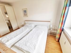 a large white bed in a room with a mirror at Apartmentvermittlung Mehr als Meer - Objekt 16 in Niendorf