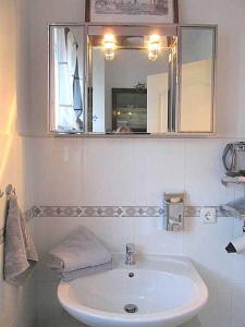 ein weißes Badezimmer mit einem Waschbecken und einem Spiegel in der Unterkunft Apartmentvermittlung Mehr als Meer - Objekt 91 in Priwall
