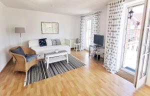 ein Wohnzimmer mit einem weißen Sofa und einem TV in der Unterkunft Apartmentvermittlung Mehr als Meer - Objekt 10 in Niendorf