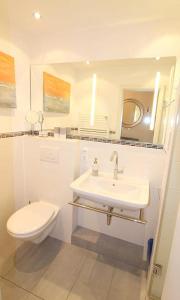 a white bathroom with a toilet and a sink at Apartmentvermittlung Mehr als Meer - Objekt 48 in Niendorf