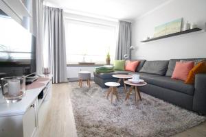 ein Wohnzimmer mit einem blauen Sofa und Tischen in der Unterkunft Appartementvermittlung Mehr als Meer Objekt 36 in Niendorf