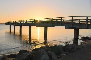 un muelle sobre el agua con la puesta de sol en Apartmentvermittlung Mehr als Meer - Objekt 73, en Niendorf