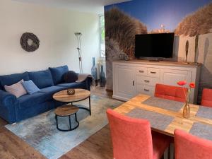 ein Wohnzimmer mit einem blauen Sofa und einem Tisch in der Unterkunft FEWO Baltrum in Bad Zwischenahn