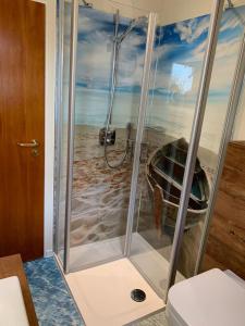 eine Dusche im Bad mit einem Gemälde eines Strandes in der Unterkunft FEWO Baltrum in Bad Zwischenahn