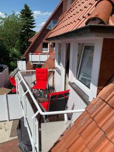 einen Balkon mit zwei roten Stühlen auf einem Haus in der Unterkunft FEWO Baltrum in Bad Zwischenahn