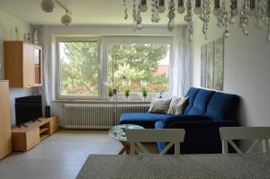 ein Wohnzimmer mit einem blauen Sofa und einem Fenster in der Unterkunft Ferienwohnung Meerzeit in Cuxhaven