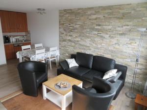 uma sala de estar com mobiliário de couro preto e uma parede de tijolos em Ferienwohnung Meerglück em Cuxhaven