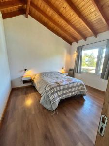1 dormitorio con cama y ventana grande en Sombra Verde en Villa La Angostura