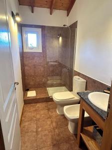 y baño con 2 aseos, ducha y lavamanos. en Sombra Verde en Villa La Angostura