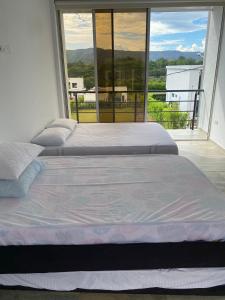 - 2 lits dans une chambre avec une grande fenêtre dans l'établissement Casa en Condominio en Carmen de Apicala, à Carmen de Apicalá