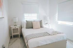 - une chambre blanche dotée d'un lit avec des draps et des oreillers blancs dans l'établissement Casita Style Apt 3 w/ Sofa Bed & Patio @ Santurce, à San Juan