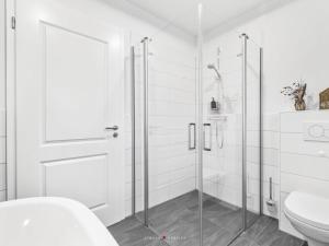 Un baño blanco con ducha y WC. en Ferienwohnung AusZeit 24 7, en Damp 21 fotos más