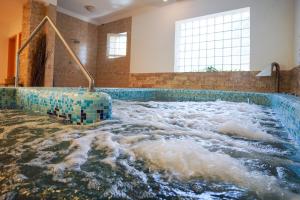 a bath tub filled with water in a room at Szalajka Fogadó és Étterem in Szilvásvárad