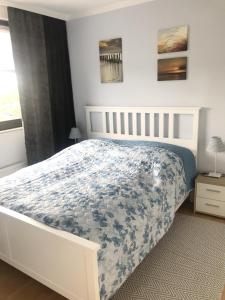 a bedroom with a white bed with a blue comforter at Ferienwohnung StrandinSicht in Damp