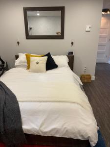 1 cama blanca grande con almohadas y espejo en Suite au centre de l’Estrie en Ange-Gardien