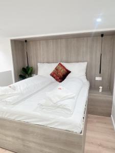 Elle comprend un grand lit avec des draps blancs et un oreiller rouge. dans l'établissement Zeus Design Loft Apartments Braunhirschen, à Vienne