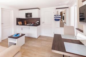 uma cozinha com armários brancos e uma mesa num quarto em Apartmenthuus König em Norderney