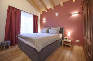 um quarto com uma cama grande e uma parede vermelha em Ferienhaus K4 in Garmisch-Partenkirchen em Garmisch-Partenkirchen