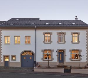 a white house with blue doors and windows at Gästehaus Cantzheim in Kanzem