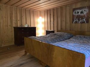 1 dormitorio con 1 cama y pared de madera en Revier mitenand im Gand, en Rüti