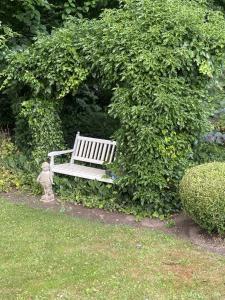 un banco blanco sentado frente a un arbusto en Waldblick, en Ratekau