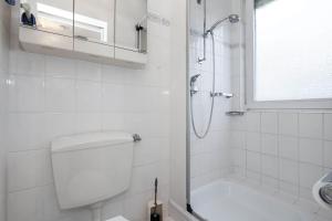 uma casa de banho branca com um chuveiro e um WC. em Gästehaus Wendland - Timmendorfer Strand em Timmendorfer Strand
