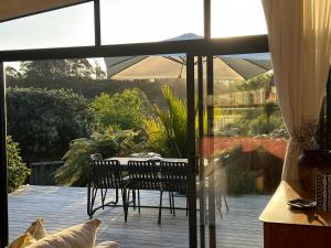 a patio with a table and chairs and an umbrella at The Driving Creek Cottage in Coromandel Town