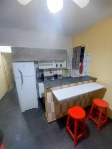 una cocina con dos taburetes rojos frente a un mostrador en kitnet Aconchegante com simplicidade, en Ubatuba
