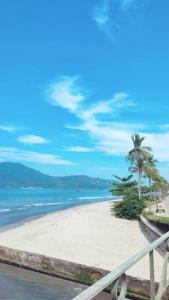 una playa blanca con palmeras y el océano en kitnet Aconchegante com simplicidade, en Ubatuba