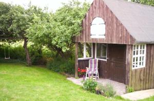 einem Holzschuppen mit einem Stuhl im Hof in der Unterkunft Wohnen unter Reet in Galmsbüll