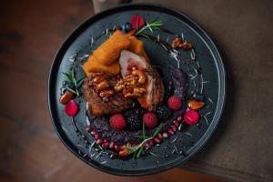 un plato de comida con carne y fruta. en Szalajka Fogadó és Étterem en Szilvásvárad